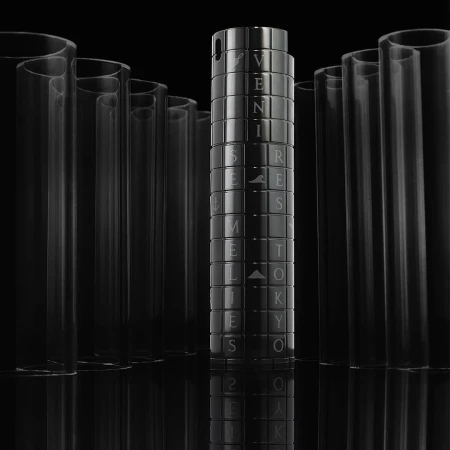 Close-up of a glossy black cylinder with text and geometric patterns, surrounded by clear tubes against a stark black backdrop.