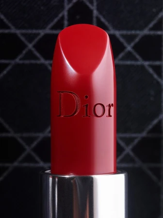 Close-up of red Dior lipstick with a silver tube against a black patterned background, capturing luxury beauty and cosmetics.