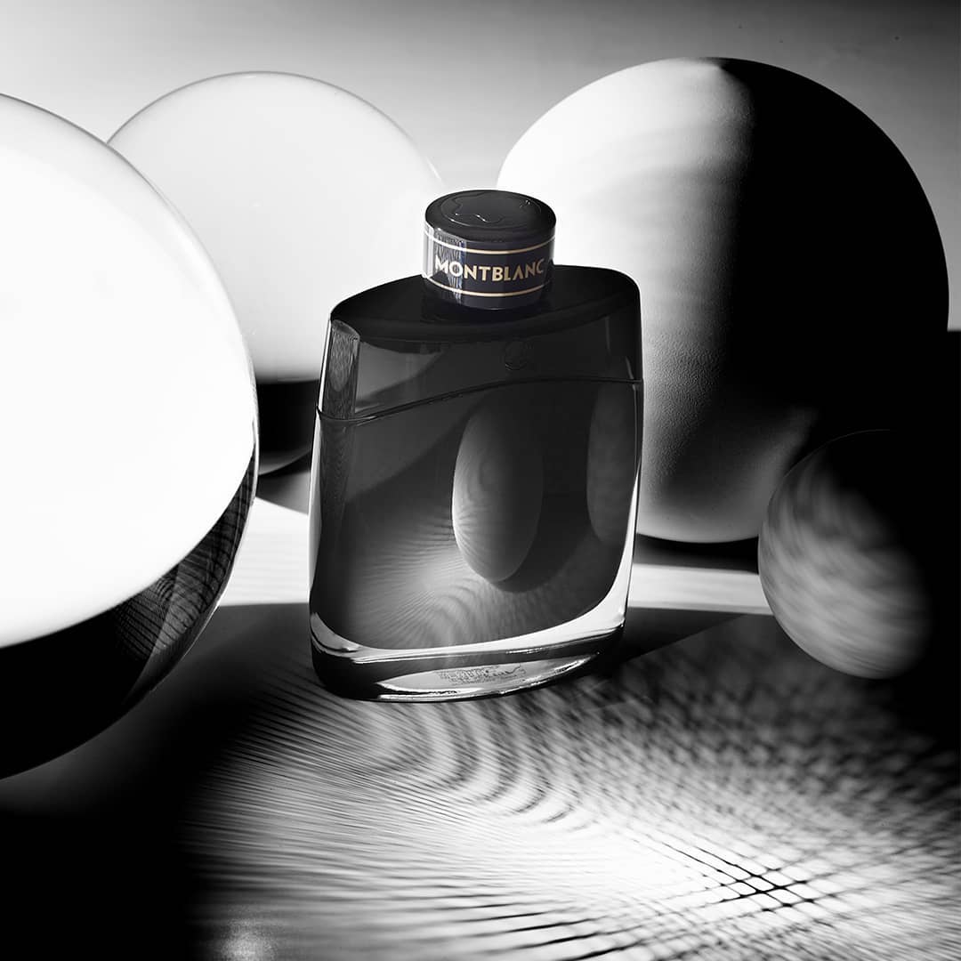 Montblanc Legend fragrance bottle in black and white, studio shot with spherical forms, product photography, men's cologne, close-up.