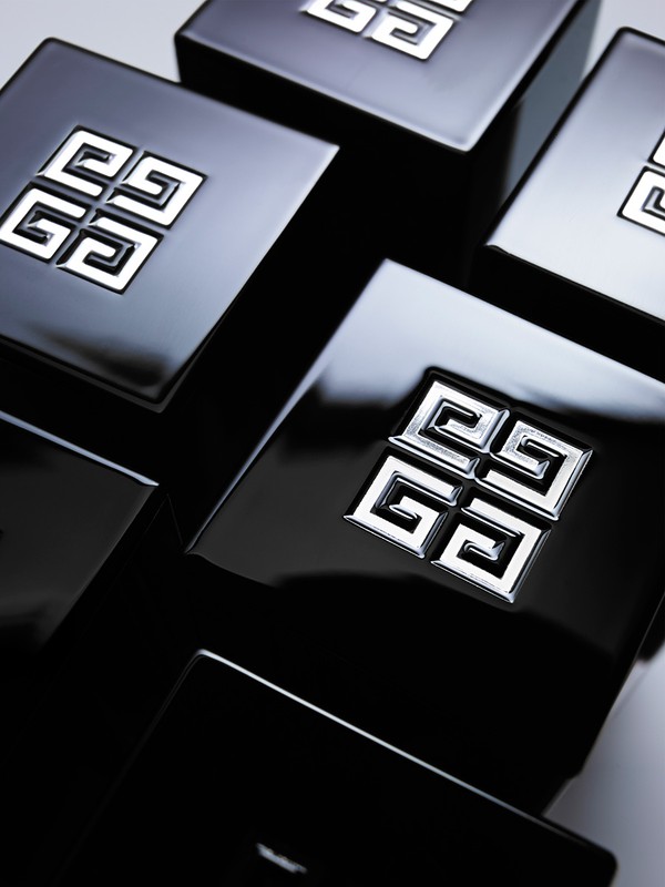 Several glossy black boxes featuring the Givenchy logo are arranged close together, creating a visually striking, high-contrast composition.
