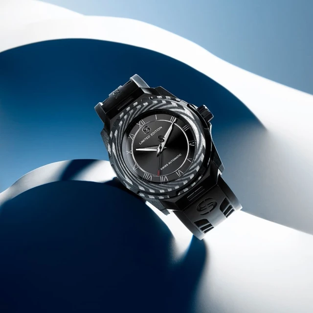 Studio shot of a black automatic wristwatch on a blue and white abstract background, showcasing its design and details.
