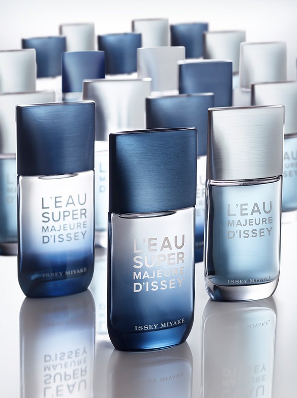 Three Issey Miyake L'Eau Super Majeure D'Issey fragrance bottles are displayed on a white surface, with multiple bottles blurred in the background.