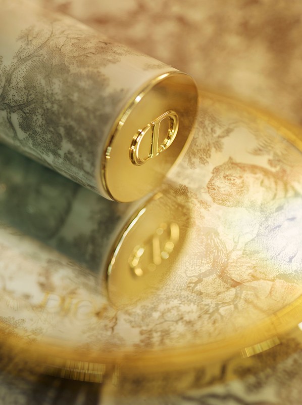 Close-up of a cosmetic container with a nature-inspired pattern and gold accents, reflecting on a shiny surface. Beauty product.