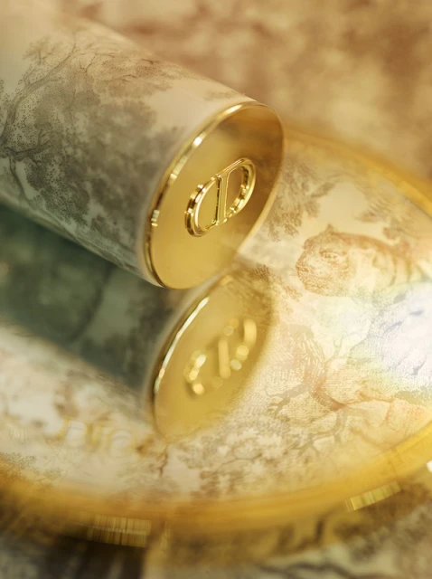 Close-up of a cosmetic container with a nature-inspired pattern and gold accents, reflecting on a shiny surface. Beauty product.
