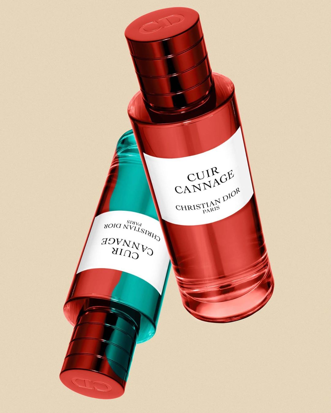 Two perfume bottles floating against a solid beige background, featuring red and turquoise glass with white labels.