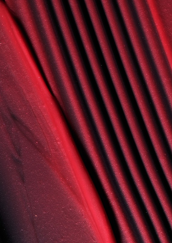 Burgundy textile fabric with diagonal pleats and a silky shimmer.