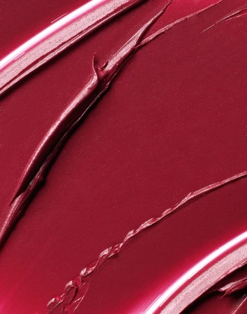 Close-up macro shot of rich crimson lipstick smeared across a smooth surface with bright specular highlights.