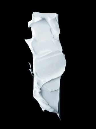 Close-up of a vertically aligned smear of a light-blue creamy substance, possibly cosmetic or skincare product, against a black backdrop.