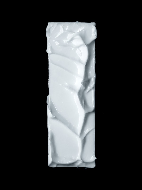 Thick white cosmetic cream textured in a vertical rectangular block against a solid black background.
