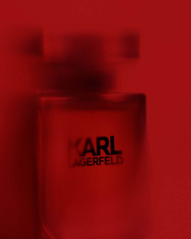 Close-up of a Karl Lagerfeld perfume bottle with a red tint and monochromatic color scheme creating a striking visual for beauty product.