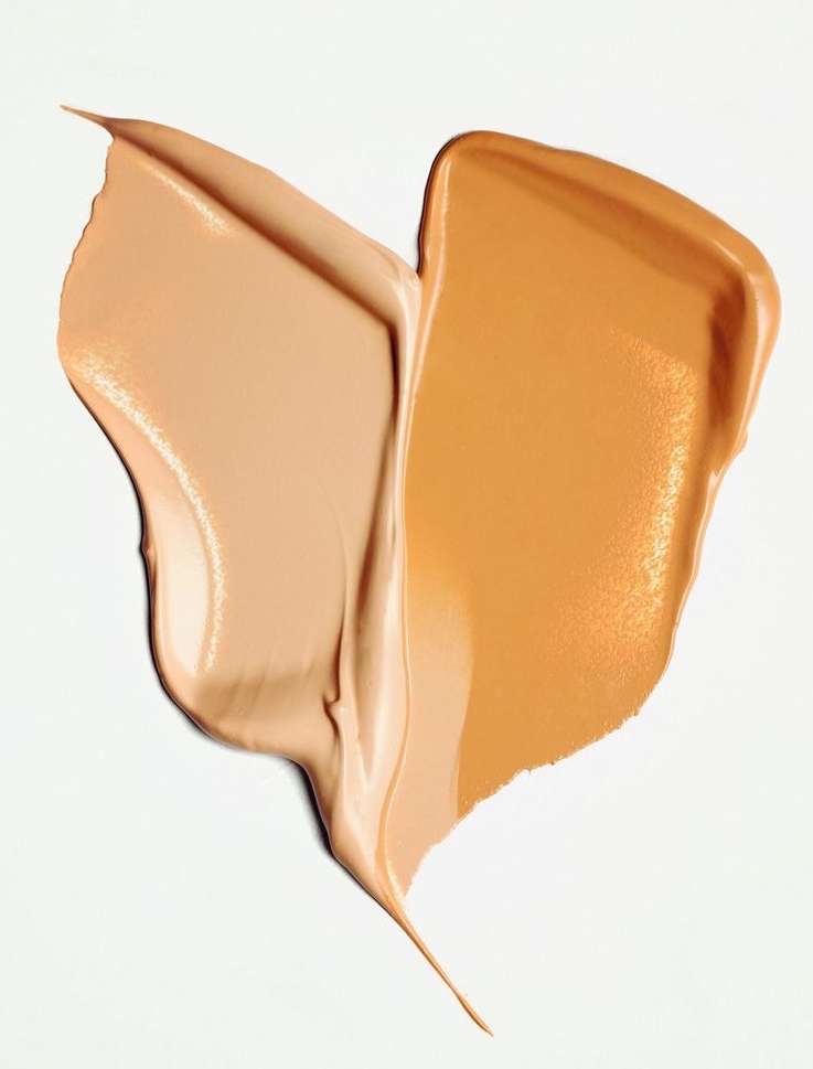 Close-up of light and medium shade foundation swatches on a white background, revealing smooth textures in a beauty product shot.