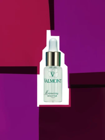 Valmont Moisturizing Booster serum bottle on a background of purple, magenta, and white geometric shapes, creating a modern beauty product shot.