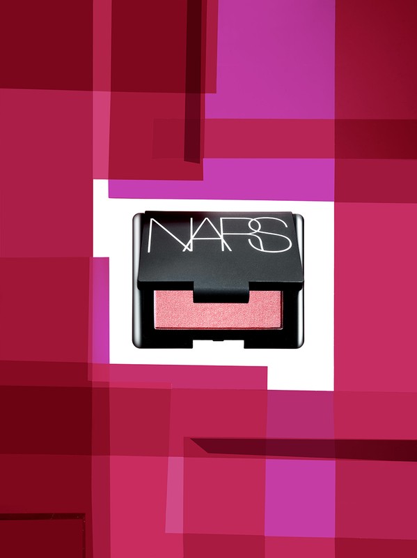 NARS blush compact on a white surface, framed by a geometric pattern in shades of pink and purple, makeup product shot.