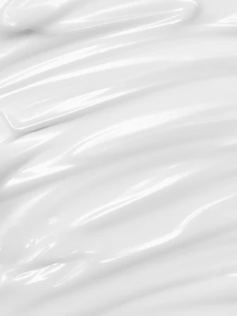 Close-up of smooth, glossy white cream or lotion, swirled to create ridges. Monochromatic, bright lighting, product shot.