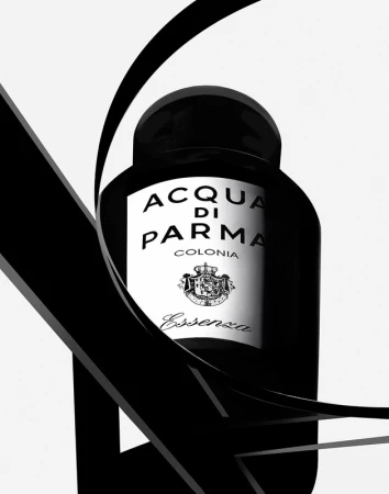 Elegant black and white studio shot of Acqua di Parma Colonia Essenza bottle with a fluid black ribbon accent on a white backdrop.