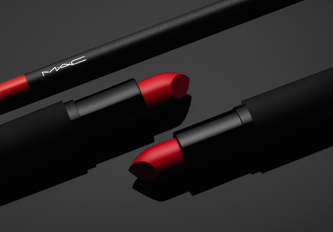 MAC lipstick and lip pencil in a studio shot, showcasing the product's red hues, black casing, and reflective surface against a dark backdrop.