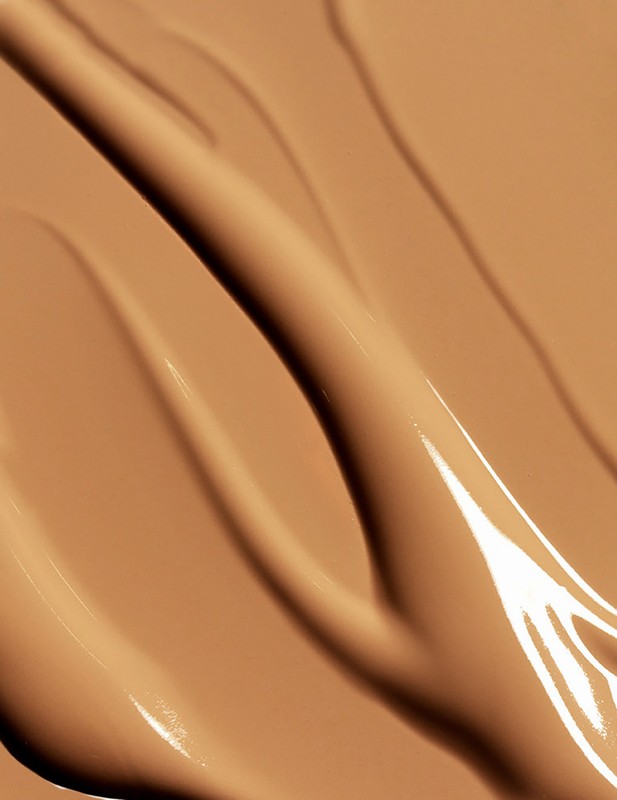 Macro close-up shot of tan-colored cosmetic foundation swatches with a glossy sheen. Beauty product background for makeup concepts.
