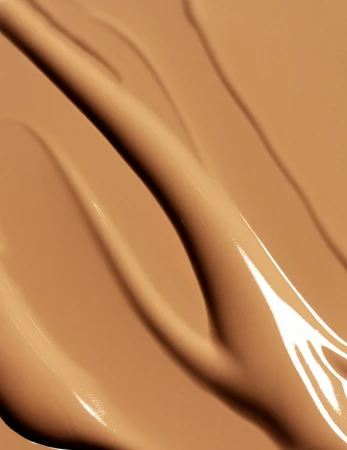 Macro close-up shot of tan-colored cosmetic foundation swatches with a glossy sheen. Beauty product background for makeup concepts.