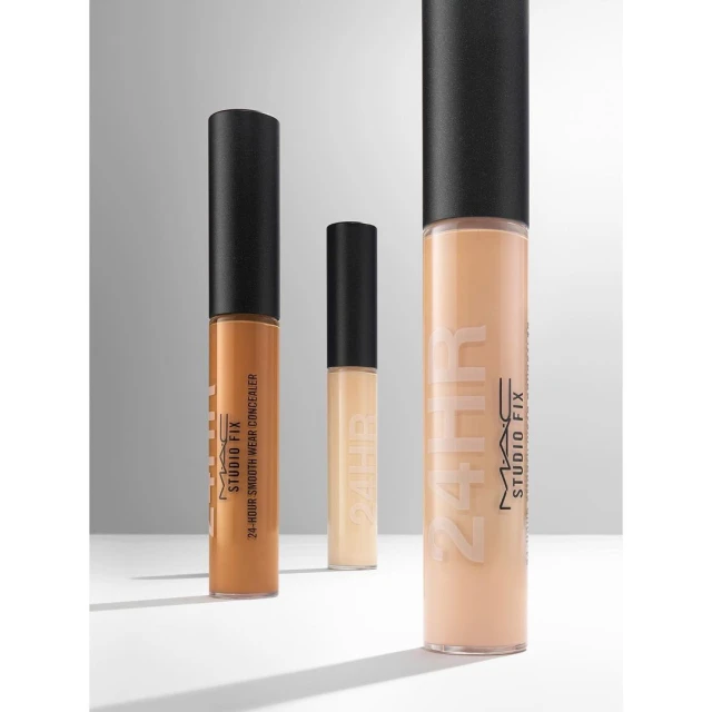 Three MAC Studio Fix concealers in varying shades are arranged against a neutral gradient backdrop in a beauty product shot.