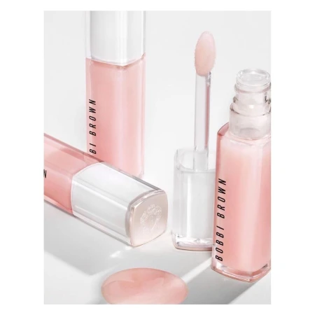 Three tubes of Bobbi Brown lip gloss are displayed with applicators on a white surface, showcasing the product's minimalist design.