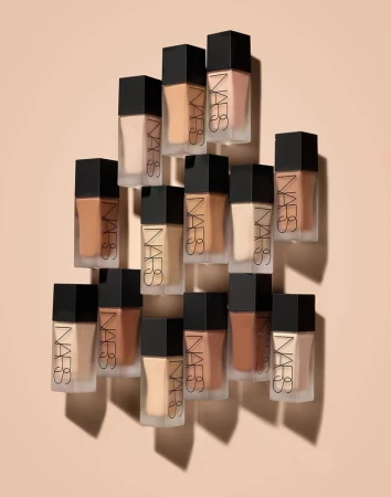 An array of NARS foundation bottles with varying shades, displayed on a neutral background, showcases beauty and cosmetic variety.