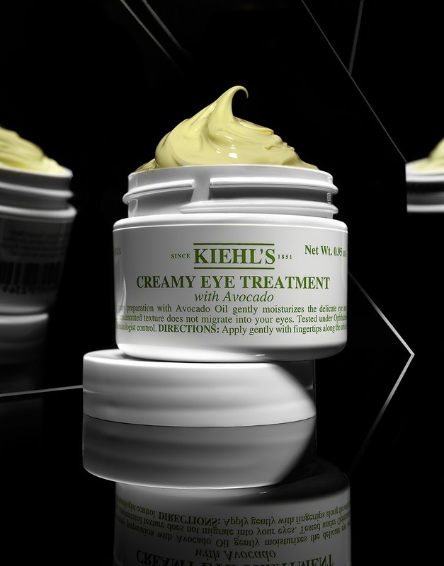Kiehl's Creamy Eye Treatment with Avocado sits in a white jar against a black background in a beauty product studio shot.