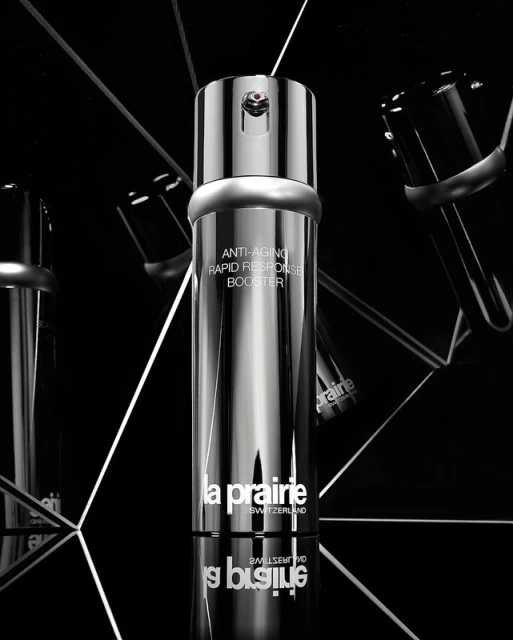 La Prairie silver skincare bottle with reflective surfaces, angled lighting, and a black background for a luxurious aesthetic.