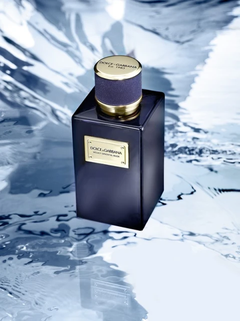 Dolce & Gabbana Velvet Oriental Musk fragrance: a dark-blue glass perfume bottle with gold accents on a marble-like blue surface.