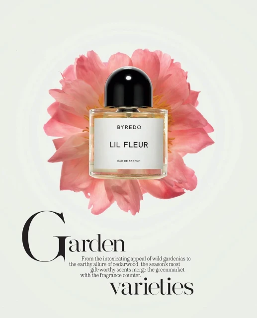 Byredo Lil Fleur perfume bottle with a black cap, set against a backdrop of a pink flower on a light backdrop. Beauty shot, studio lighting.