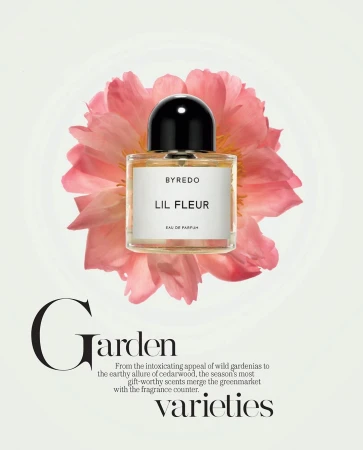 Byredo Lil Fleur perfume bottle with a black cap, set against a backdrop of a pink flower on a light backdrop. Beauty shot, studio lighting.