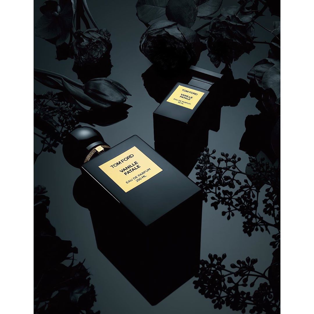 Two black perfume bottles, TOM FORD VANILLE FATALE, surrounded by black roses and foliage, creating a luxurious and dark aesthetic.