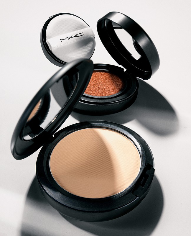 Makeup powder compacts with black cases and light-colored powder, on a white surface. Beauty and cosmetics product photography.