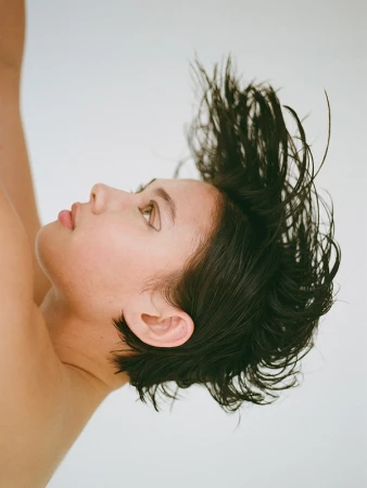 Close-up profile of a woman with dark hair swept upward against a plain white background