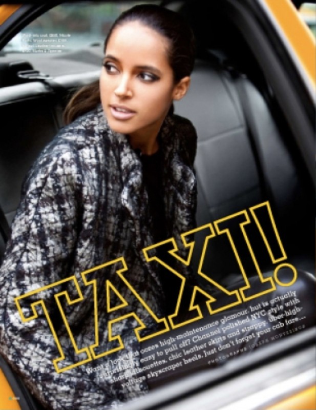 Fashion editorial shot of an adult woman in a textured coat sitting inside a yellow taxi cab looking out the window, natural daylight.