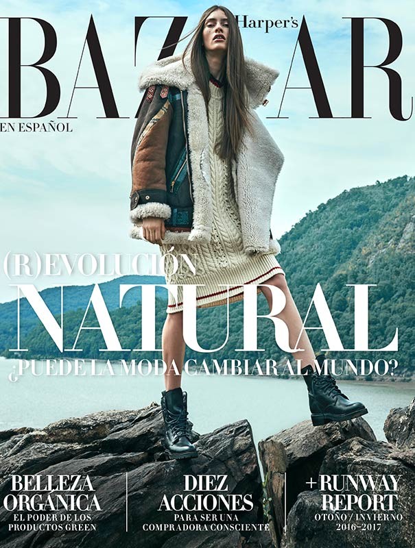 Bazaar En Espanol cover featuring a female model in a sweater dress, shearling jacket, and boots, standing on rocks with a water and mountain background.
