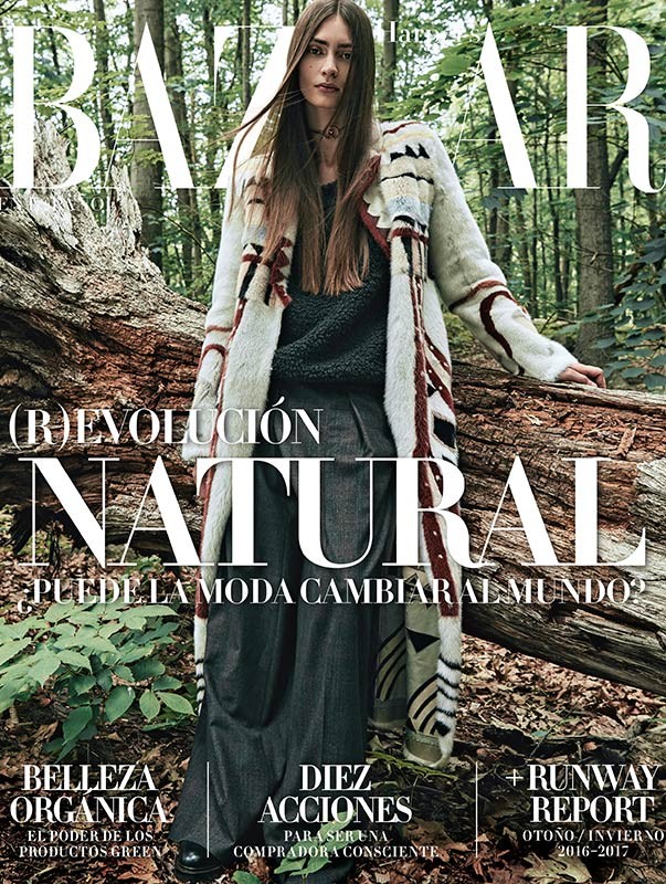 Bazaar magazine cover featuring a Caucasian model wearing a long patterned coat in an outdoor forest setting with fallen trees.