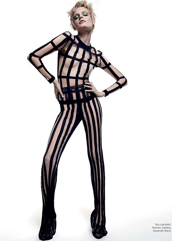 Fashion model poses in a skin-tight black-and-nude striped catsuit. The design features a grid pattern on the torso and solid black shoes.