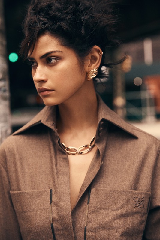 Close-up portrait of a woman wearing a brown collared shirt and gold chain necklace with makeup by Hector Simancas.