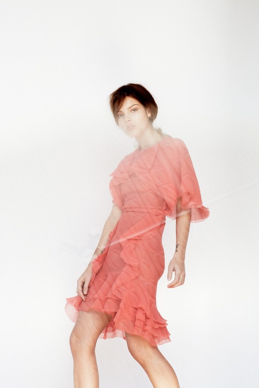 Woman in ruffled short dress with slight motion blur against a white background in a studio setting. Fashion photography.
