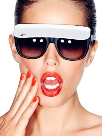 Glamorous woman with surprised expression wears novelty sunglasses and bright lipstick, posing on a white background.