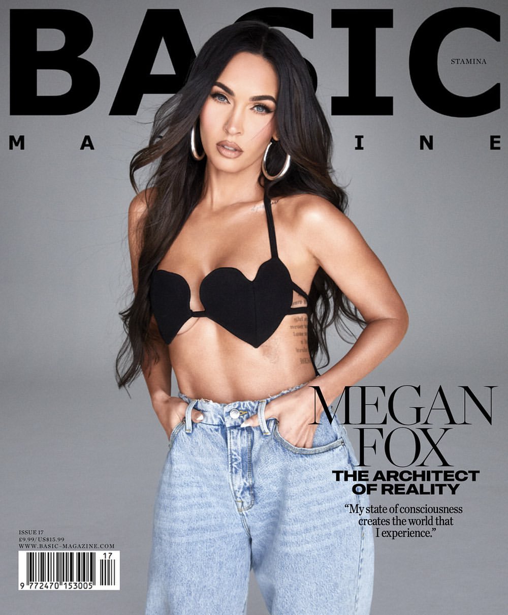 Magazine cover featuring Megan Fox wearing a black heart-shaped top and blue jeans against a gray backdrop. Her long hair flows down.