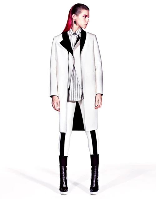Fashion model in a stark white coat with black accents, paired with striped shirt and white leggings, in a studio setting, high contrast.