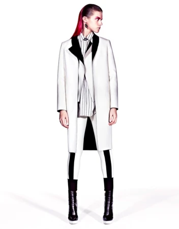 Fashion model in a stark white coat with black accents, paired with striped shirt and white leggings, in a studio setting, high contrast.