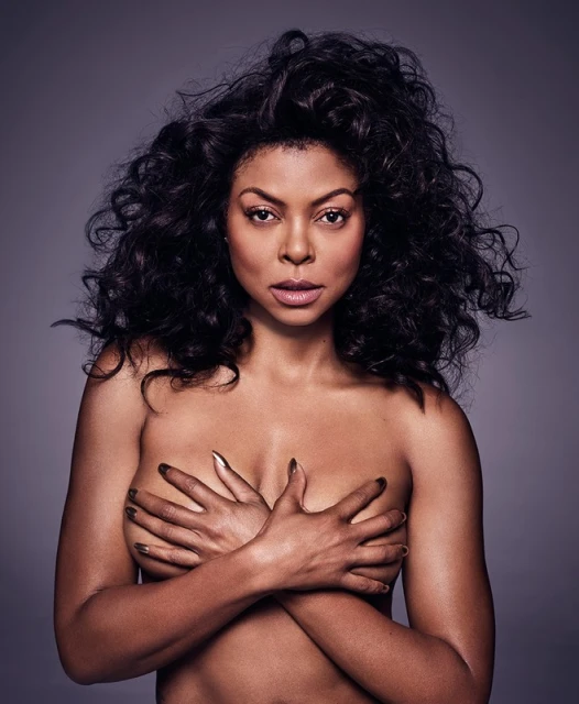 Striking portrait of an adult woman with voluminous dark curly hair, fair skin, and hands crossed over her bare chest against grey backdrop.