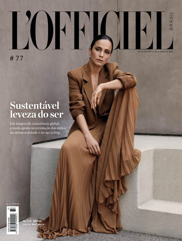 Woman in brown blazer and pleated skirt seated on concrete steps for magazine cover