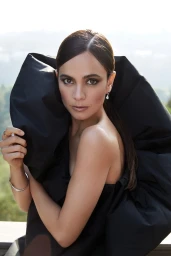 Portrait of a woman wearing a black sculptural top with a high collar, photographed by James White.