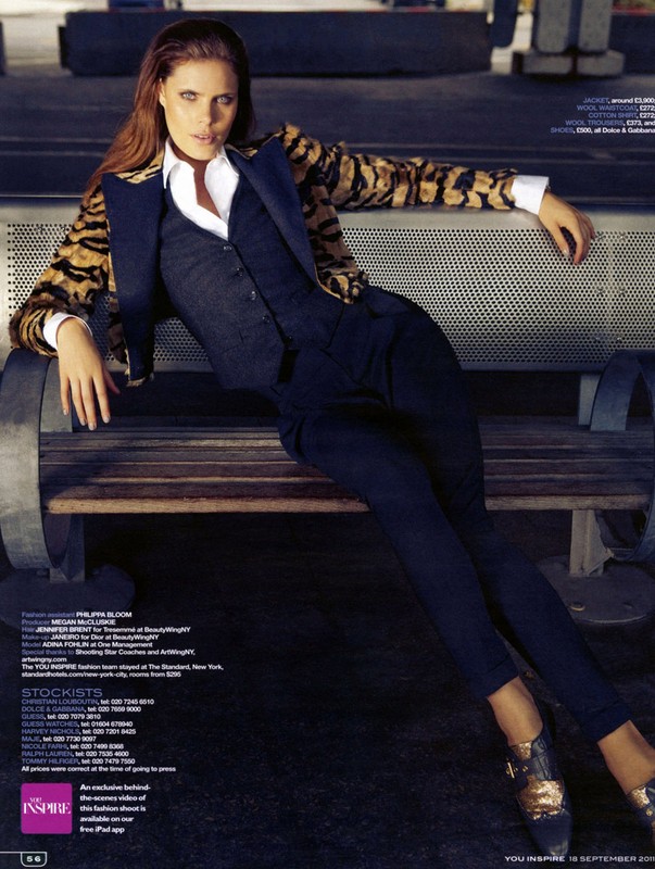 Woman in dark waistcoat and patterned jacket leaning on an outdoor bench in Los Angeles with makeup by Janeiro