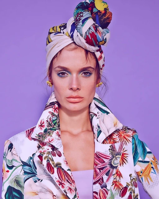 Portrait of a woman with floral head wrap and blazer against a purple background, beauty shot, fashion and style concept.