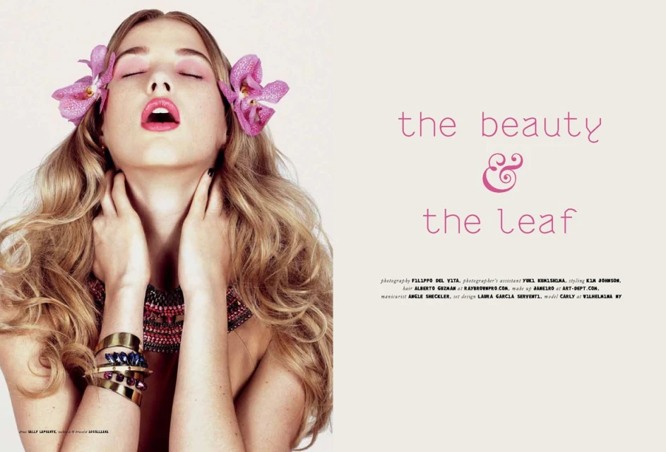 Fashion editorial shot of a young woman with blonde wavy hair, closed eyes, fair skin, light pink eyeshadow, and pink orchid hair accessories.