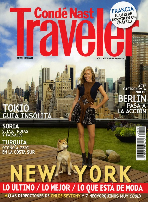 Condé Nast Traveler magazine cover featuring a model in a black dress with a Shiba Inu, set against a backdrop of New York City buildings.